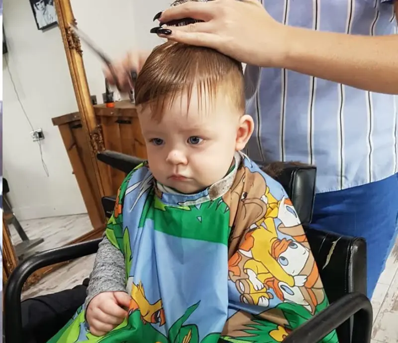 A young child receiving a haircut at Moustache Barbers